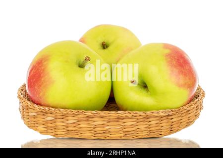 Three organic juicy apples in a straw plate, macro, isolated on white background. Stock Photo