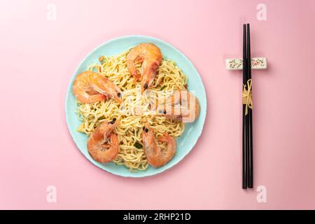 Instant Noodles on a pink background with Shrimps Asian Thai food fusion style easy dish street food popular. top view bright pink background color. Stock Photo