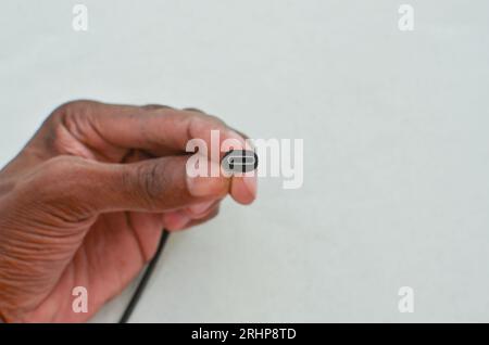 Black USB Type-C cable detail highlighted on a clear surface, perfect for modern technology concepts. Close-up black USB Type-C cable providing speed Stock Photo