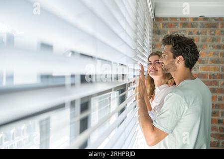 Couple looking through blind Stock Photo