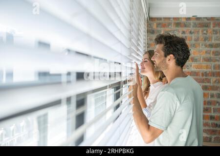 Couple looking through blind Stock Photo