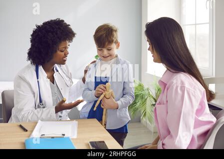 Caring female pediatrician talking to small boy patient and his mother in hospital Stock Photo