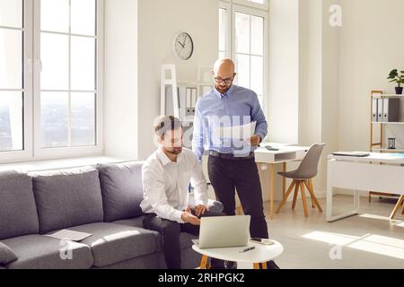 Two young business men at work in office talking and having discussion. Stock Photo