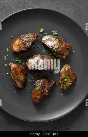 Grilled chicken liver on plate over dark stone background. Top view, flat lay Stock Photo