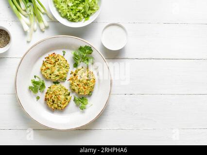 Zucchini fritters. Vegetable vegetarian zucchini pancakes on plate over white wooden background with free space. Top view, flat lay Stock Photo