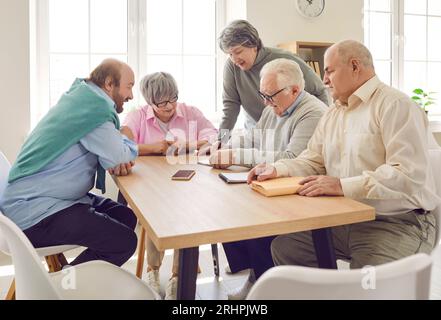 Cheerful retired friends sitting around table at home Stock Photo