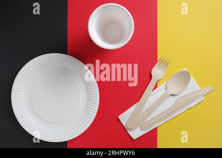 Paper plate, spoon, fork, knife and glass on colored background. Disposable tableware Stock Photo