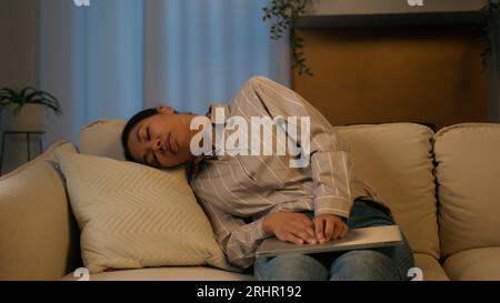 Tired exhausted African American businesswoman night working laptop from home overworked woman fall asleep on couch sick weary sleeping female flopped Stock Photo