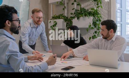 Team leader explain business project to colleagues in office boardroom show presentation graphs charts on interactive board multiracial businessmen Stock Photo