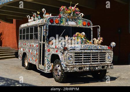 A decorated school bus, with a mosaic of stained and colored glass, stands outside of the American Visionary Art Museum in Baltimore, Maryland Stock Photo