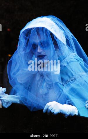 A young woman dresses up as a ghost in a bridal gown and veil costume for a Halloween festival in Sleepy Hollow, New York Stock Photo