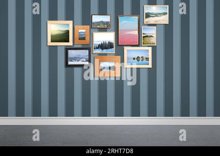 Many beautiful landscapes in frames on striped wall in room Stock Photo