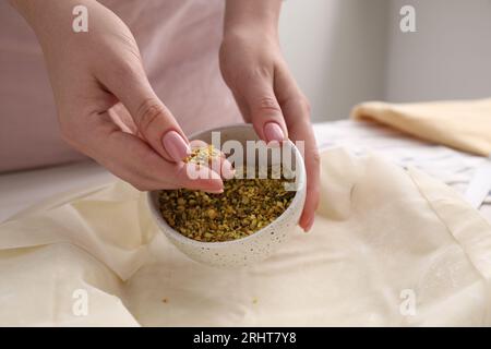 Woman putting filling into baking dish with dough to prepare baklava, closeup Stock Photo