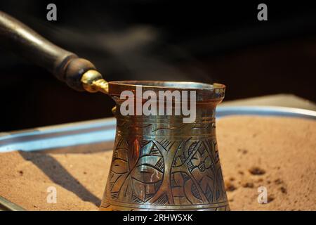 Traditional Turkish coffee in metal cezve,  with hot sand. Copper vintage pot with fresh coffee Stock Photo