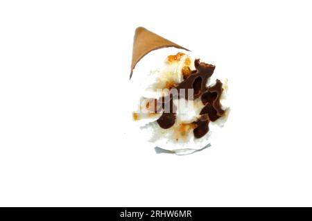 Ice cream vanilla cone with topping of chocolate chips pieces, nuts and caramel in a crispy wafer cones, selective focus of melting cold ice cream twi Stock Photo