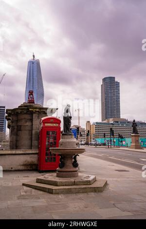 Vertical photo of 1 One Blackriars office building with a red classic telephone booth in fron and the Blackfriars Bridge in London, United Kingdom Stock Photo