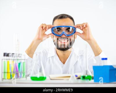 Young male scientist putting on his biosafety glasses before starting an experiment in a laboratory. Stock Photo