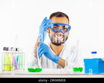 Young male scientist putting on his gloves before performing a science experiment in a lab Stock Photo