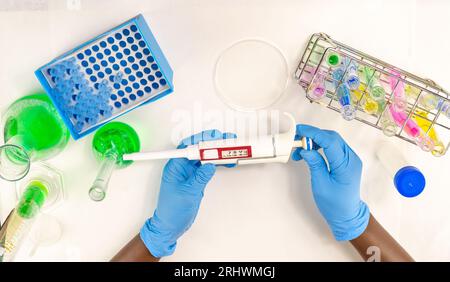 A close up of female hands holding a micropipette showing the different measurements with lab glassware and equipment in the background Stock Photo