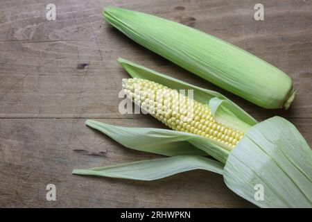a close up of freshly picked sweet corn on a wooden table Stock Photo