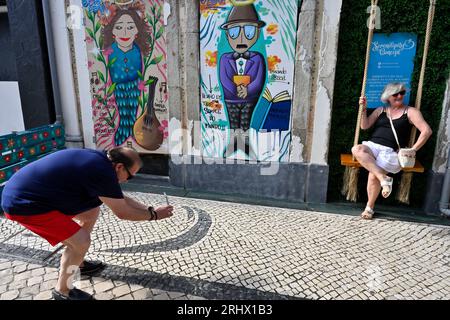 Quirky little spot with swing and “Serendipity Concept” street art which attracts tourists, man photographing woman with phone Stock Photo