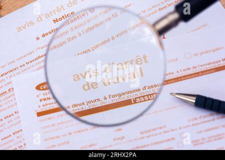 France: Close-up through a magnifiying glass of an official sick leave form ('Avis d'arrêt de travail') from the French social security Stock Photo