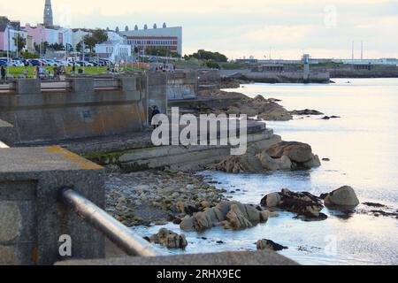 A photo of a walk along the edge of a coast and the landscape of buildings behind it. Stock Photo