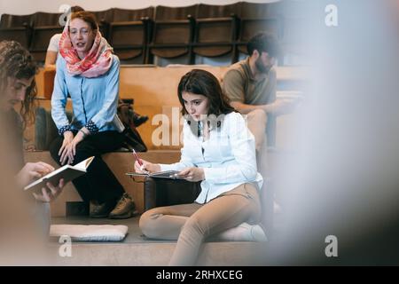 Alluring female employee thinking before she writes down in a notebook Stock Photo