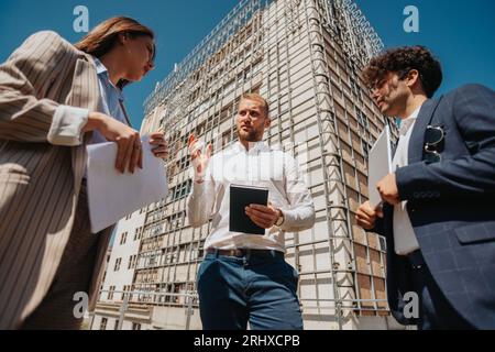 Construction specialists walking through construction site. Discussing paperwork, planning and development details Stock Photo