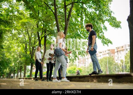 Positive, smart, college students discussing while standing on a sidewalk in the city Stock Photo