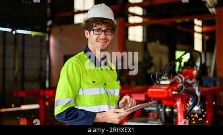 Young mechanical technician using tablet checking machine at warehouse Stock Photo
