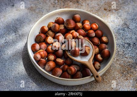 Top view of fresh chestnuts placed in ceramic bowl with a spoon in a concrete background Stock Photo
