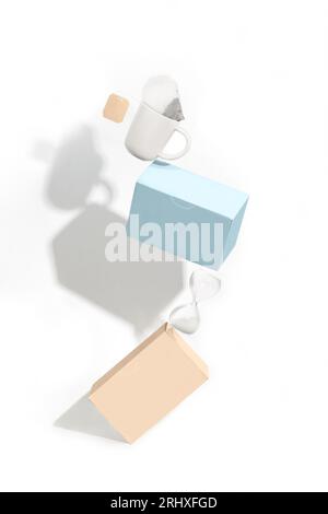 Balancing composition with boxes and a white tea cup against white background Stock Photo