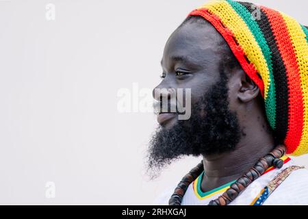Side view of African American man in colorful hat standing and looking away against white background Stock Photo