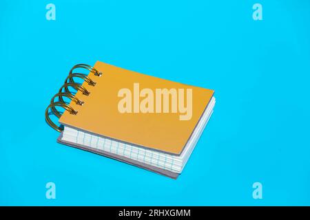 Top spiral bound yellow hardcovers parallel line papers notebook placed against blue background Stock Photo