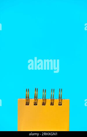 Closeup of yellow spiral notepad placed on bright blue background representing concept of office supplies Stock Photo