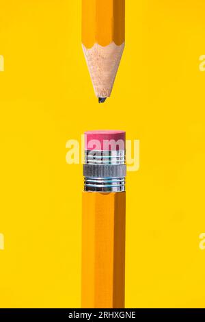Flat lay composition of orange colored wood pencils with sharpened broken tip and red eraser fitted in metal ring on top placed against yellow backgro Stock Photo