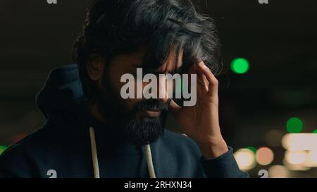 Close up stressed worried ill sick unhappy sad Arabian man touching painful head suffer headache pain unhealthy Indian guy male at parking suffering Stock Photo