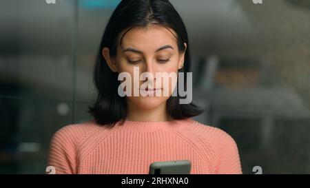 Serious multiracial woman using smart phone in shopping mall. Female girl surfing social media cellphone buying online store chatting mobile chat Stock Photo