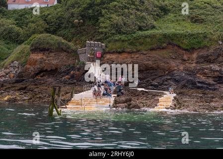 Herm, Channel Islands. 11 June 2023.  The Rosaire Steps, Herm at low tide  seen from an approaching passenger ferry inbound. Passengers wait onshore. Stock Photo