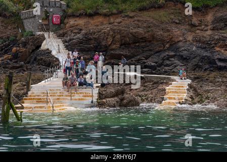 Herm, Channel Islands. 11 June 2023.  The Rosaire Steps, Herm at low tide  seen from an approaching passenger ferry inbound. Passengers wait onshore. Stock Photo