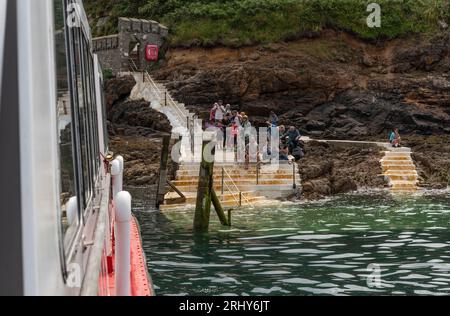 Herm, Channel Islands. 11 June 2023.  The Rosaire Steps, Herm at low tide  seen from an approaching passenger ferry inbound. Passengers wait onshore. Stock Photo