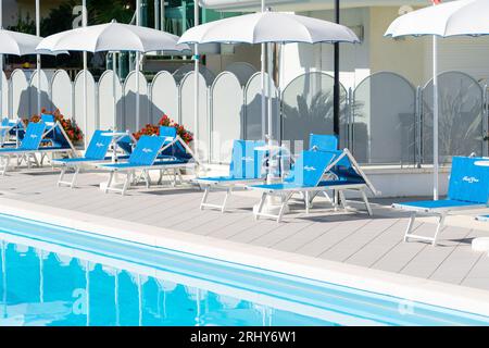 Grab bars ladder in the blue swimming pool, empty chaise longue, private swimming pool Stock Photo