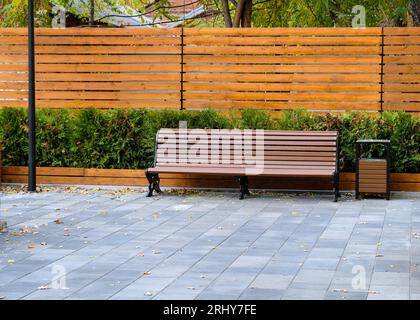 Wooden bench in the park in the city. comfortable wooden bench of brown slats with a smooth transition. Arrangement of the park comfortable places for Stock Photo