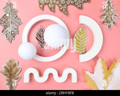 Gypsum figures of different shapes with dry autumn leaves on a pink background top view. Abstract background with geometric shapes for product present Stock Photo