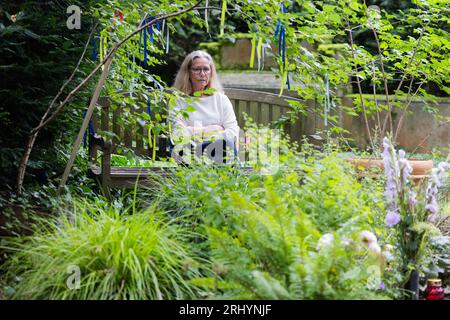Cologne, Germany. 18th Aug, 2023. Annegret Fleischel sits on a bench at her son's grave at Melaten Cemetery. The 70-year-old spends many hours on a bench at her son's grave. This summer, Cologne has a topic that sets tempers racing: should 'wild benches' be removed from the Melaten cemetery for celebrities, or would that be heartless? (to dpa KORR 'The great Cologne cemetery bench debate' from 20.08.2023) Credit: Rolf Vennenbernd/dpa/Alamy Live News Stock Photo