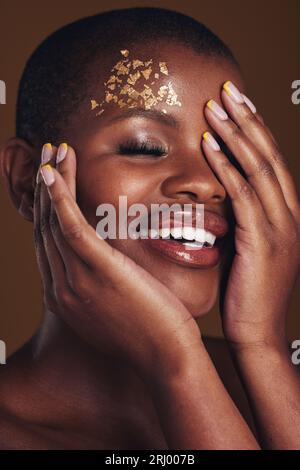 Gold, Glitter Portrait And Black Woman Beauty With Makeup And Skincare Mask  In Studio With Sparkle Cosmetics. Brown Background, Funny And Model With  Golden Paint For Skin Glow And Creative Shine Stock