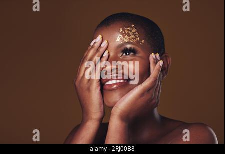 Gold, Glitter Portrait And Black Woman Beauty With Makeup And Skincare Mask  In Studio With Sparkle Cosmetics. Brown Background, Funny And Model With  Golden Paint For Skin Glow And Creative Shine Stock