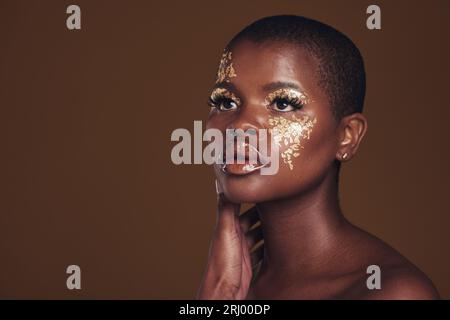 Art, glitter and black woman with gold makeup on brown background, face  paint and cosmetics. Shine, glow and African model in studio for beauty  Stock Photo - Alamy