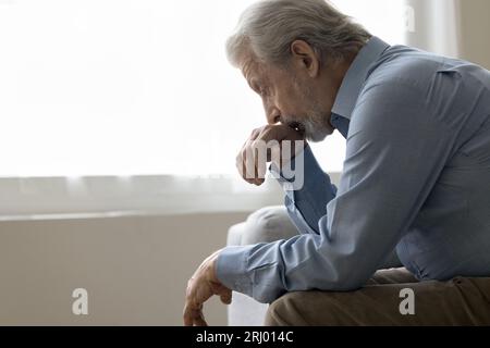Depressed elder retired man sitting on home couch Stock Photo